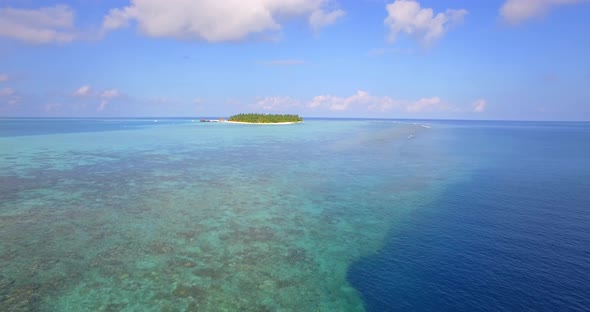 Aerial drone view of a man and woman couple snorkeling over the coral reef of a tropical island