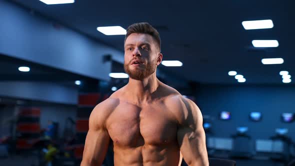 Athletic man in gym is posing to the camera. Bodybuilder with perfect body.