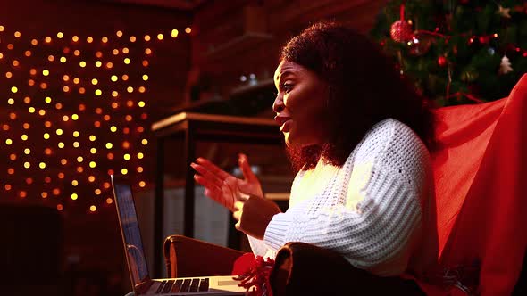 Brazilian Woman Connection with Her Family Online in Evening Room with Garlands Lights Backgroind