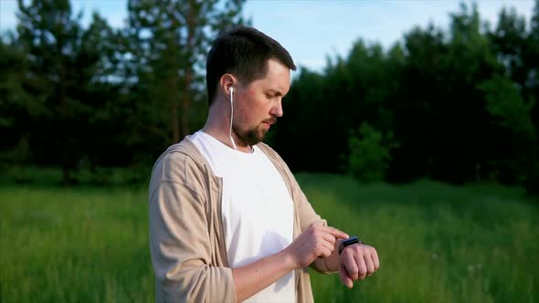 A Man Checks on a Smart Watch How Many Kilometers He Ran in the Park in Summer