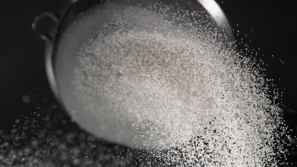 Dusting flour on black background. Slow Motion.