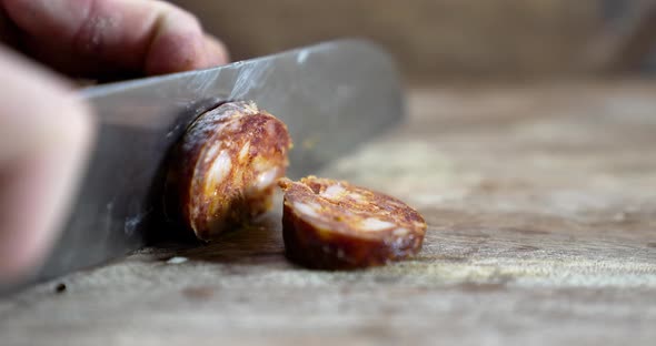 Man cuts into thin slices fatty sausage. Shooting closeup of Chef cutting salami with knife