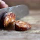Man cuts into thin slices fatty sausage. Shooting closeup of Chef cutting salami with knife - VideoHive Item for Sale