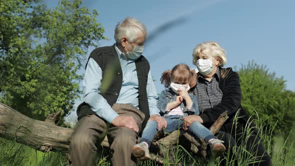 Grandparents with Granddaughter in Medical Masks in Park. Coronavirus Quarantine