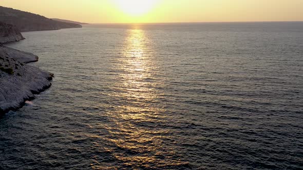 Flying Over the Sea During the Sunrise Near the Rocky Coastline of Thassos