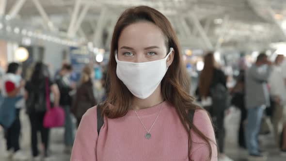 Portrait of a Woman in Medical Mask Looking Straight at Camera in Airport Terminal Preventing