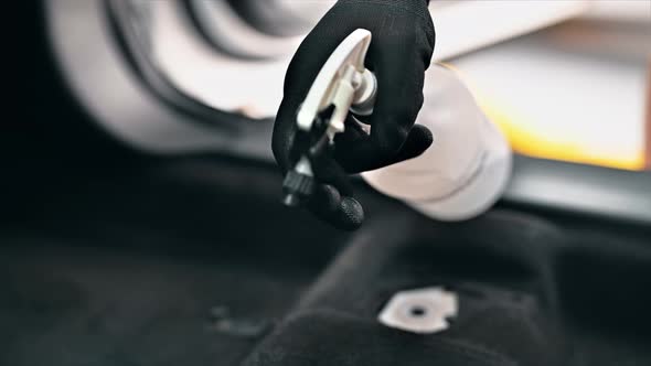 Working cleaner at car wash. Cleaning interior using a spray with chemical solution. Slow motion