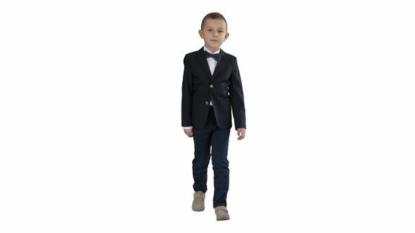 Little boy in a costume with a bow tie walking on white background.