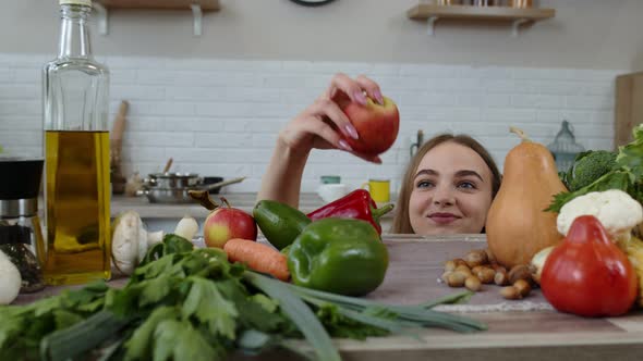 Girl Peeping From Under the Table and Stealing Fresh Apple and Eating It. Weight Loss, Diet Concept