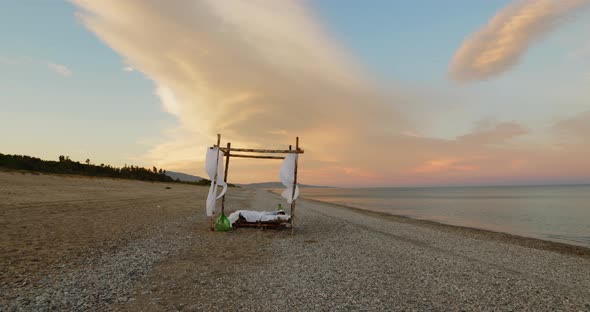 Young girl sleeps in a canopy bed at sunset on the beach near the ocean