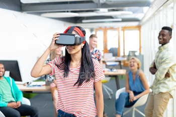  virtual realty headset while diverse colleagues standing in background at office