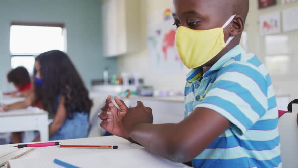 Boy wearing face mask sneezing in class at school