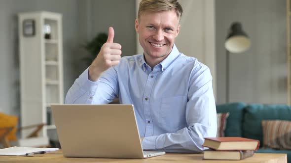 Thumbs Up By Businessman Looking at Camera at Work