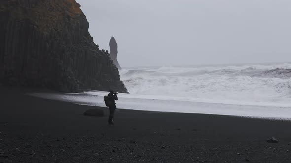 Man Photographing Rough Stormy Sea Crashing Into Rocks