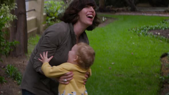 Caucasian baby running to woman in garden