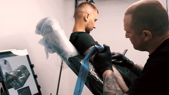 Male Tattoo Artist Tattooing a Client