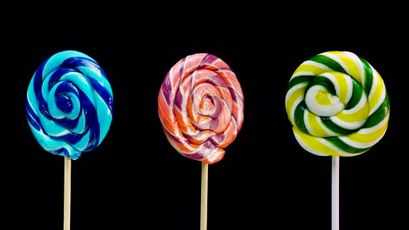 Three Different Lollipops Lollipop Green On A Stick Spinning On A Black Background.
