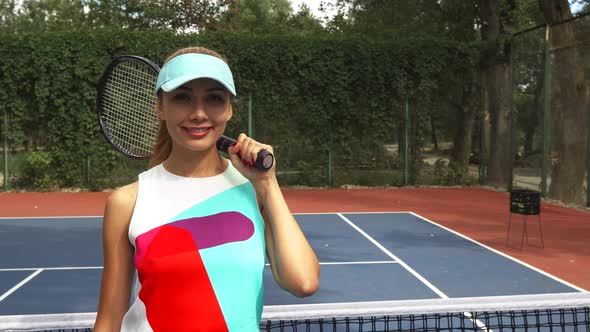 Girl with a Racket Smiling and Offering a Tennis Ball To Camera