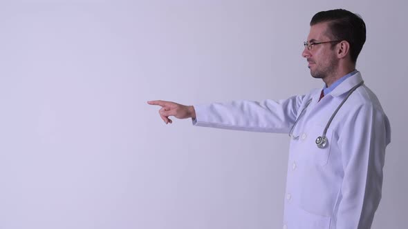 Profile View of Young Happy Hispanic Man Doctor Pointing Finger