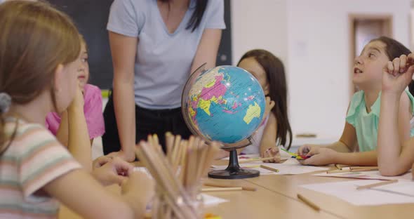 Female Teacher with Kids in Geography Class Looking at Globe alt