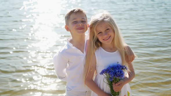 Boy gives flowers to girl, happy children, romantic gift to little girl, brother and sister