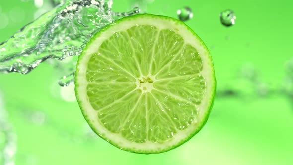 Super Slow Motion Detail Shot of Rotating Fresh Lime Slice and Splashing Water at 1000Fps