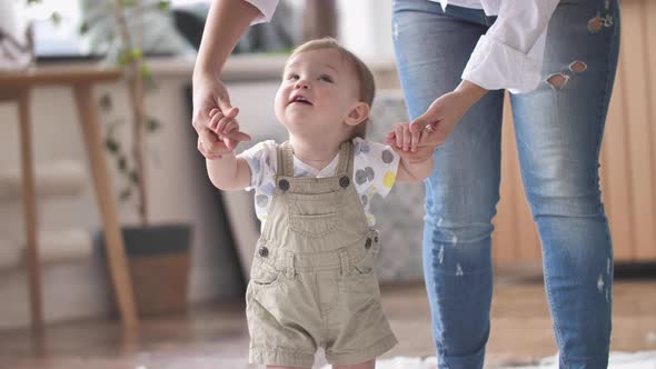 Baby Boy Taking First Steps with Mom's Help Learning to Walk at Home