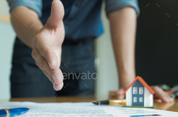 oin hands with customers to close sales.Model houses and documents placed on the table.