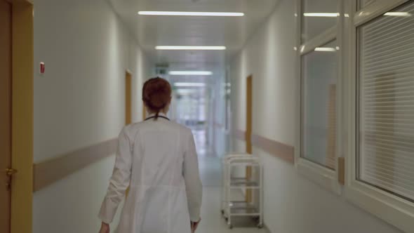 A Masked Doctor Walks Down the Corridor of the Hospital