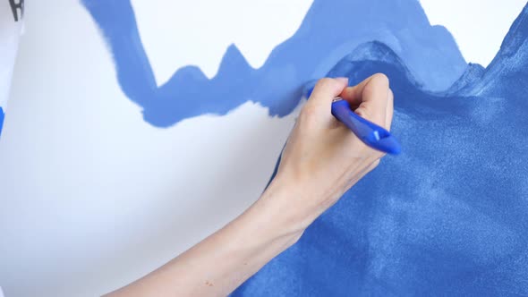 close-up female hand paints mountains on the wall