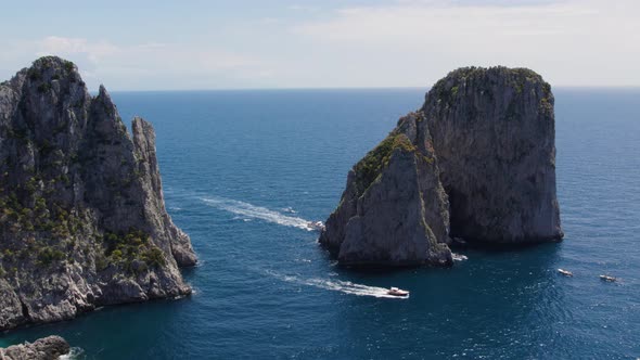 Yachts Boating around the Faraglioni Sea Stack Rock Formations in Italy