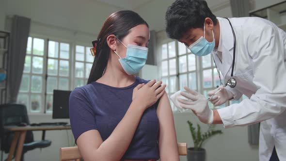 Doctor In Safety Gloves And Protective Mask Is Making A Vaccine Injection To A Female Patient