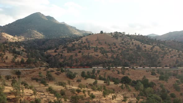 Aerial view, cargo train driving by Sierra Nevada mountains in California