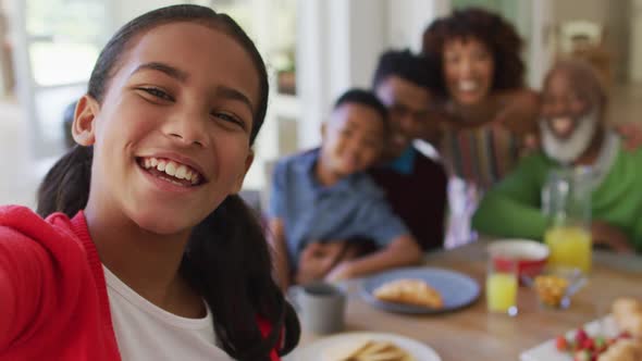 African american girl taking a selfie while having breakfast with her family at home