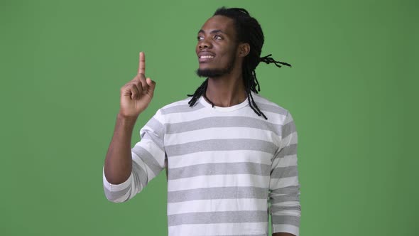 Young Handsome African Man with Dreadlocks Against Green Background