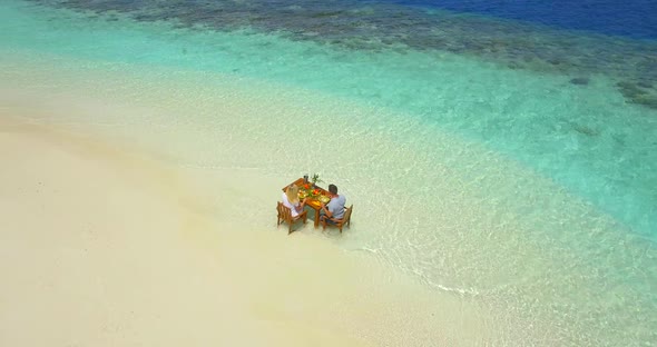 Aerial drone view of a man and woman eating breakfast on a tropical island beach