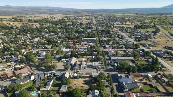 Aerial dolly in flying above Trevelin valley houses with Andean mountains in background, Patagonia A