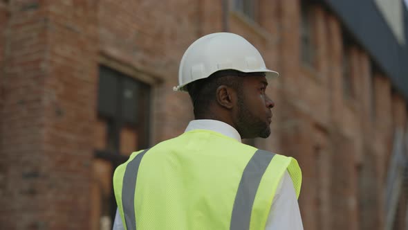 Male Builder Walking Along Wall of Unfinished Building