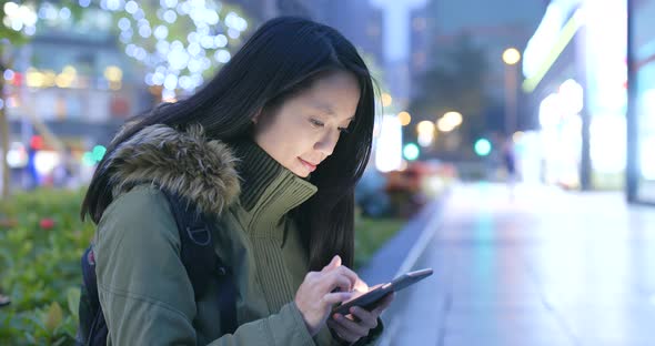 Asian woman use of mobile phone in city at night