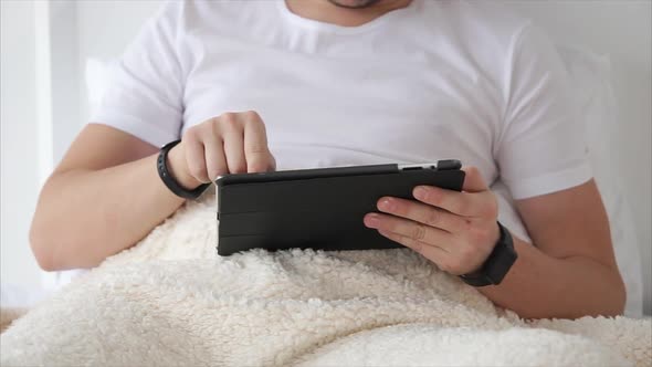 Man Is Relaxing with Tablet in Bed.