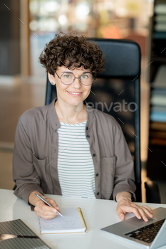 Happy brunette girl writing down her ideas on page of notebook