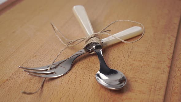 Tied with rope spoon and fork on a wooden cutting board 