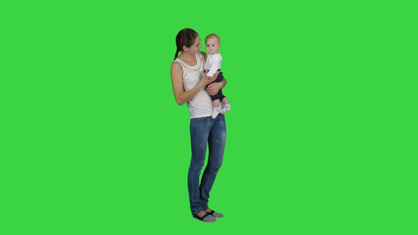 Cute Baby Boy in Mothers Hands Looking To Camera on a Green Screen, Chroma Key.