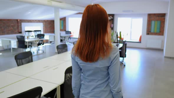 Back View of a Woman Walking Confidently Through Co-working Space