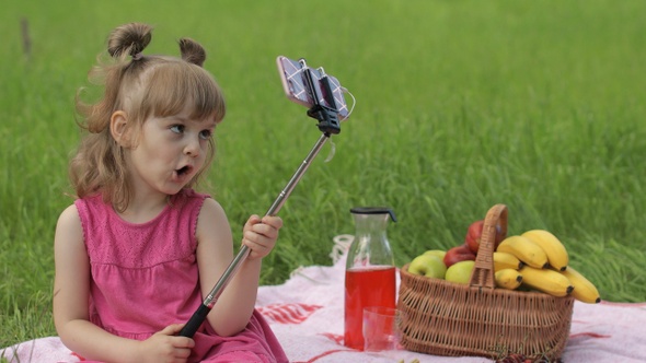 Weekend at Picnic. Girl on Grass Meadow Makes Selfie on Mobile Phone with Selfie Stick. Video Call