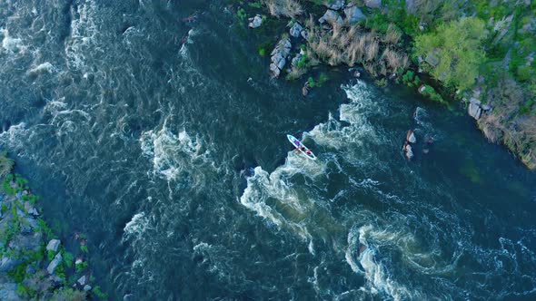 Aerial View of a Kayak Boat Rushing Along with a Stormy Stream Between the Stones at High Speed