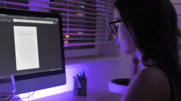 Young Woman College Student Working Late, Doing Homework on Computer in Ambience of Her Room at Nigh