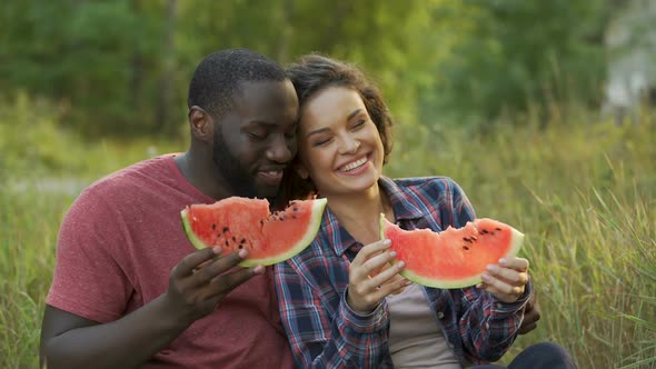 Happy couple enjoying big slices of yummy watermelon, beneficial fruit diet