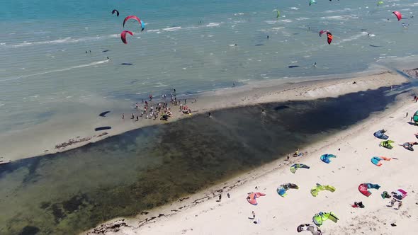 Aerial Footage of Many Kitesurfers in the Sea and People Watching Them, 