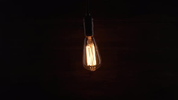 Man Turn on and Off an Old Retro Lamp with His Hand on Wooden Background. Man Enters Barn or Old